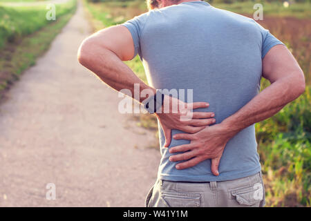 People, healthcare and problem concept - a man suffering from pain in back or reins outdoor Stock Photo