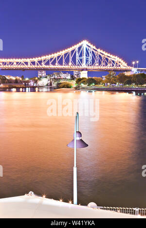 Dark river and a bridge with Street light and fences at night  with blue sky in the Brisbane City, Queensland, Australia. Stock Photo