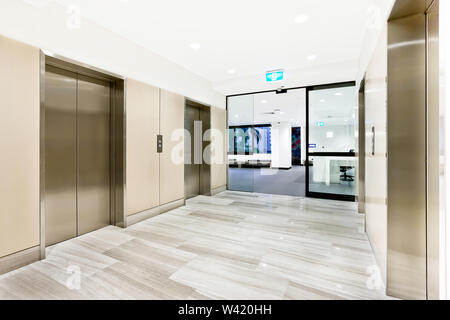 Modern silver elevator in a luxury building with open glass door to another area Stock Photo