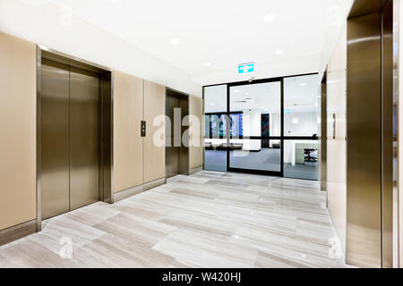 Modern silver elevator in a luxury building with closed glass door to another area Stock Photo