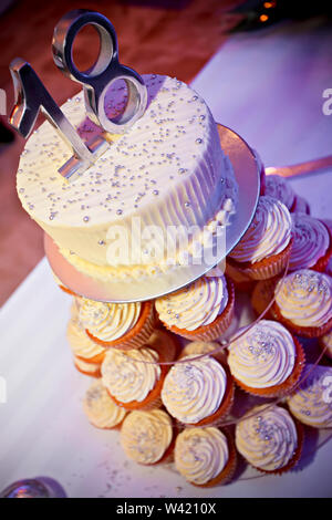 Delicious tower birthday cake with cupcakes in the base and a white creamy cake on top with digits 18. Stock Photo