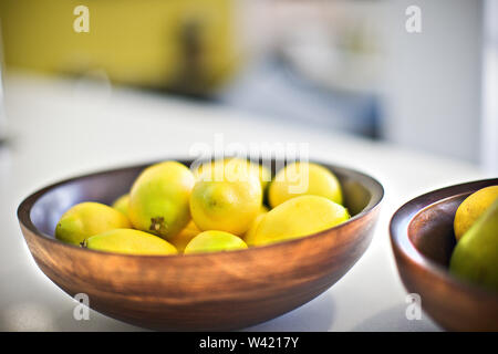 Yellow lemon on the clay bowl or plate with blurred background close up in a modern house kitchen Stock Photo