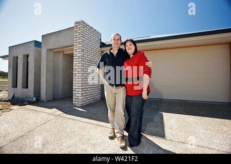 Man and woman standing near home, infront of a classic house, weather is good, no clouds on sky,sunlight around the area. Stock Photo