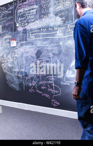 Guy with a blue dress looking at a blackboard in a classroom or a lab Stock Photo