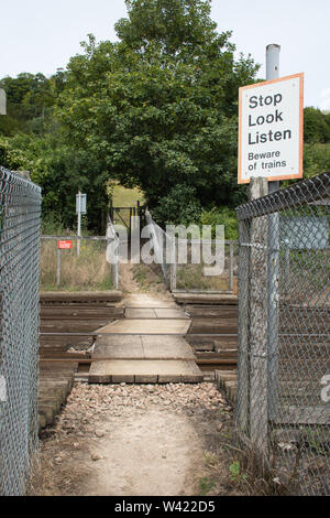 Path crossing a railway track with a safety warning sign, Stop Look Listen, Beware of trains, UK Stock Photo