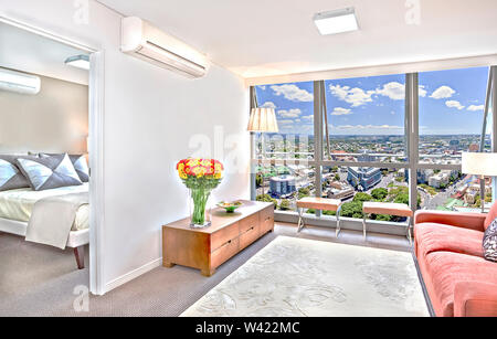 Luxurious living area  with big and fancy sofas near city, beautiful town view can see through the glass windows, there is a flower pot on table, chai Stock Photo