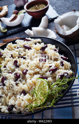 close-up of Jamaican Rice and Red Beans cooked with coconut milk seasoned with garlic, onions and creole spice in a bowl with ingredients at the backg