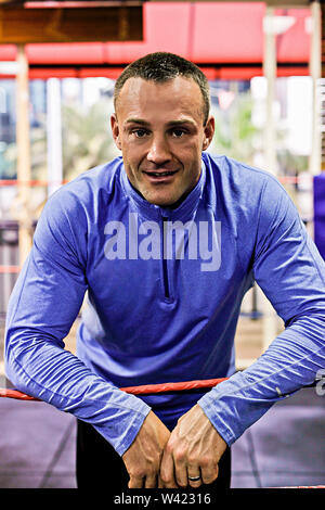 Boxing trainer standing and thinking something, inside room of a luxury gym, heavy exercise tools near wall, he looks like body builder, wearing blue Stock Photo