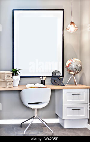 Classic study table made in wood with a book and flower vases next to plastic letter and globe model over the big picture and hanging light Stock Photo