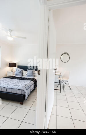 View of a well organized study and bedroom space with a tiled floor and mirrors on both walls Stock Photo