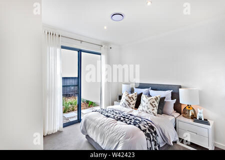 Luxury bedroom with white decoration including blankets and pillows near lamps and walls Stock Photo