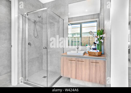 Luxury bathroom closeup with the shower and washing area, room is illuminated from sunlight and yellow light from the ceiling, colorful area. Stock Photo