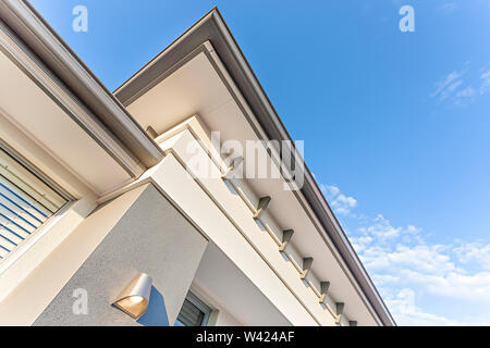 Luxury house view from the ground with a roof, low angle view of roof in large house with a blue sky, there is a rainwater drainage pipe, walls are co Stock Photo