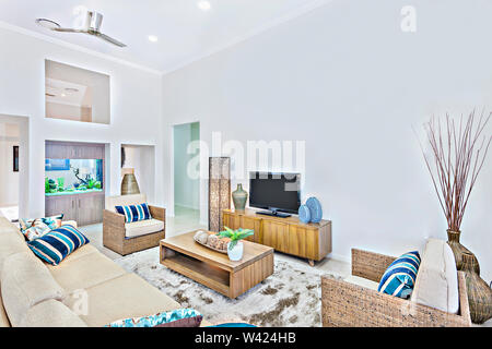 Room with comfortable look and fish tank, walls are painted in white color, comfortable sofa set  with wooden table, television near chairs, confy car Stock Photo