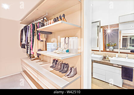 Luxury clothing store of a house or hotel with attached bathroom including shoes for men and women on the rocks beside to the washroom including mirro Stock Photo