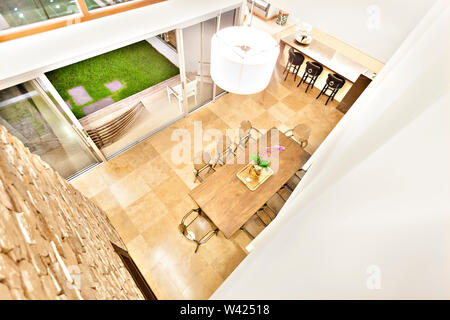 High angle view from upstairs to the patio area with outdoor entrance to the green lawn garden through the glass door under white color flashing light Stock Photo