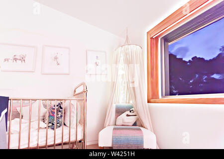 Cotton toy like a pillow which is animal shaped swan or duck on the cushion chair with a net and light in it, the baby bed has white blankets and colo Stock Photo