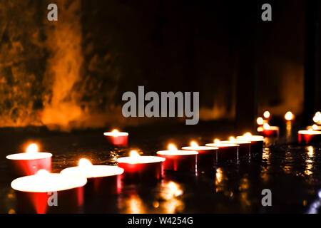 Close up of a burning candle light reflected on the stone floor Stock Photo