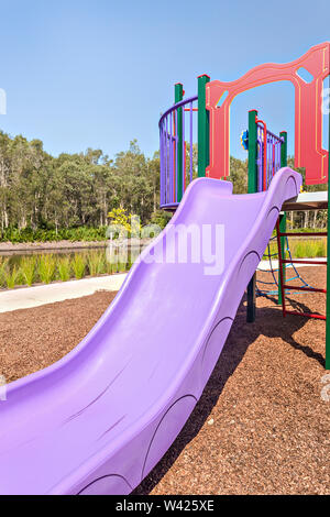 Childrens play ground with equipments near forest, colorful area with sunlight, no clouds on sky, green trees can see in jungle, lake near lawns. Stock Photo