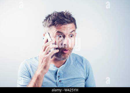Handsome young man surprised using mobile phone Stock Photo