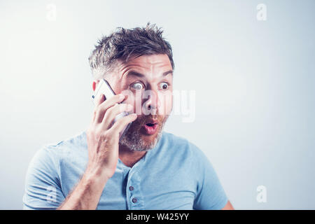 Handsome young man surprised using mobile phone Stock Photo