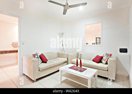 Luxury sofa set near wooden table, comfortable furnitures with designs, walls are white color, pillows on chairs, inside rooms of a apartment. Stock Photo