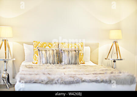 Bed with lamps flashing including pillows and wool blanket, there are two table lamps with made in wooden around on the silver surface, Stock Photo