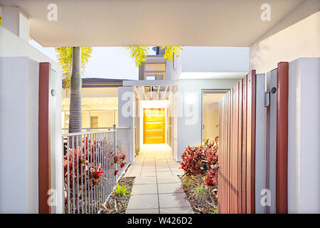 Modern home entrance with flower trees and tile floor, garden have big trees and flower plants, luxury house with facilities, fence is made with metal Stock Photo