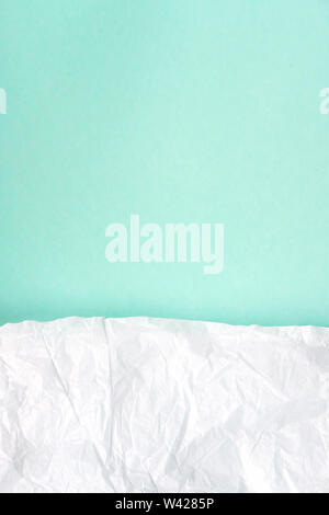 Crumpled white parchment paper on bright blue, turquoise background top view. Rough, wrinkled, damaged paper texture. Abstract design, creased, aged style art, wallpaper, backdrop, background Stock Photo