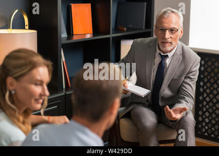 Smiling attractive psychoanalyst talking to his male patient Stock Photo