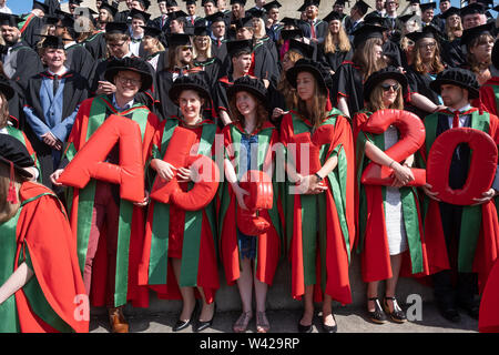 Higher education in the UK - successful PhD doctoral students at the graduation ceremony at Aberystwyth university, after receiving their degrees,  wearing their traditional tudor style bonnet caps and  red coloured  gowns. July 2019 Stock Photo