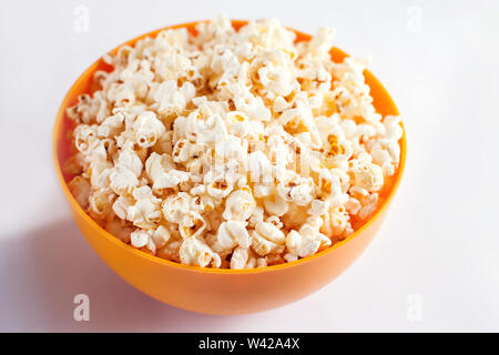 An orange bowl with popcorn isolated on white background. Food concept Stock Photo