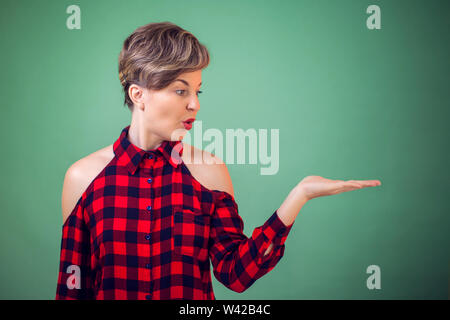 People and emotions -a portrait of surprised young woman holding something on her hand Stock Photo