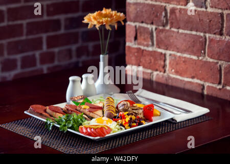 Full English Breakfast including sausages, grilled tomatoes and mushrooms, egg, bacon, baked beans and bread. Stock Photo