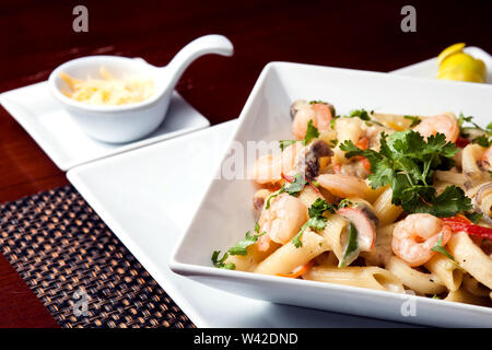 Penne (pasta) with shrimps/prawns and sausage in pomodoro (tomato) sauce - Italian cuisine, cooking, culinary (traditional authentic taste). Stock Photo