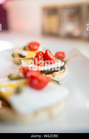 Italian appetizer of corn cracker topped with baked egg and juicy grilled aubergine and cherry tomatoes. Stock Photo