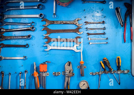 A lot of different wrenches on the blue wall background Stock Photo