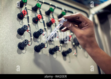 Closeup of male electrician examining fusebox with multimeter probe Stock Photo