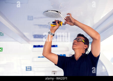Building, renovation, technology, electricity and people concept - builder with screwdriver fixing socket Stock Photo