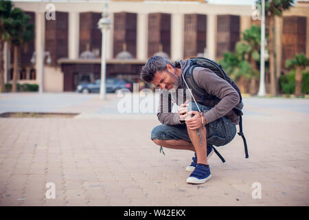 Close up of a man sitting and holding his knee in pain due to injury outdoor. People, health care, medical concept Stock Photo