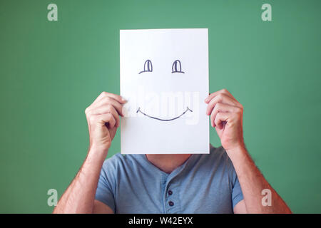 A portrait of man holding a card with smiling face. People, emotions and lifestyle Stock Photo