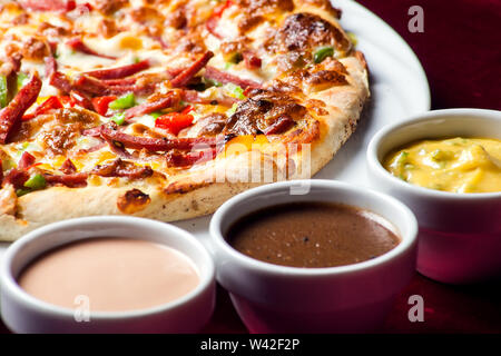Delicious pizza with with sauces on the table in cafe. Food concept Stock Photo