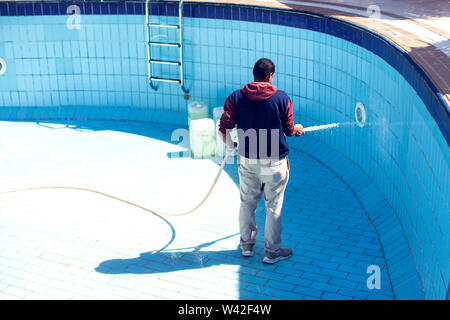 Service and maintenance of the pool. Man cleans the pool. Stock Photo