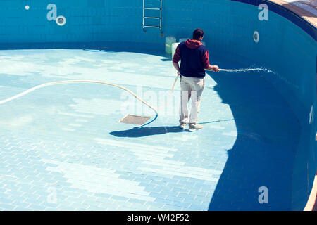 Service and maintenance of the pool. Man cleans the pool. Stock Photo