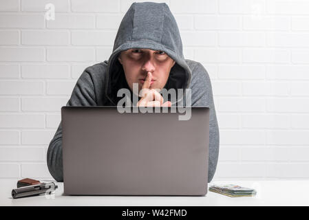 portrait of a criminal hacker with a notebook, weapon and money concept photo Stock Photo