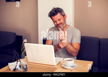 Man holding his wrist pain from using computer. Office syndrome hand pain by occupational disease. People, health care and technology concept Stock Photo