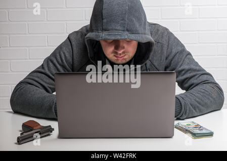 the attacker steals personal data in the computer, the hacker in the hood at work Stock Photo