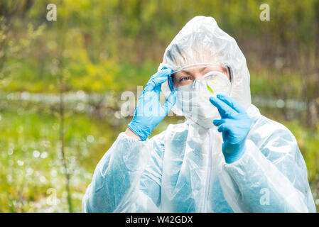 chemist researcher in protective clothing examines infected plants from a forest lake Stock Photo