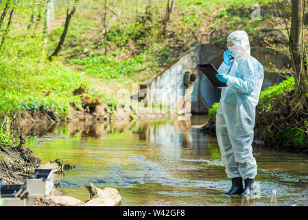 scientist doing research on the environment and water in the sewer creek Stock Photo