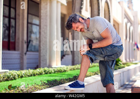 Man having a knee pain while walking on the street. Healthcare, medicine, people concept Stock Photo